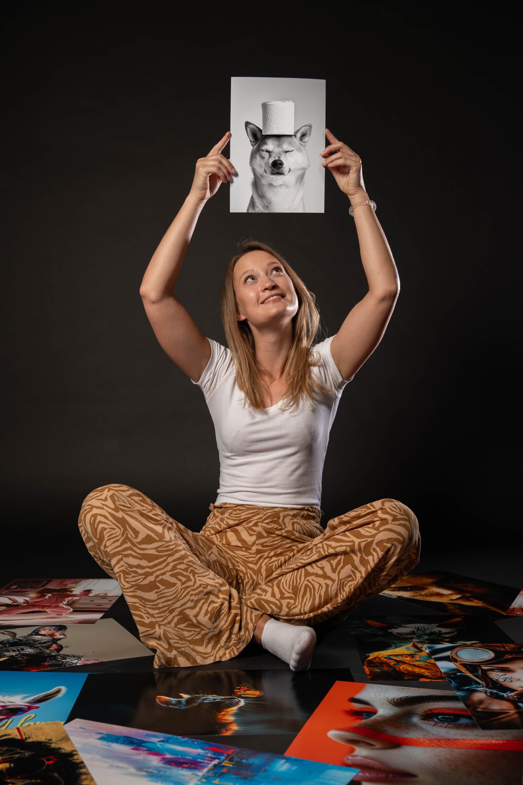 Dekle sedi med fotografijami in visoko drži eno v rokah.